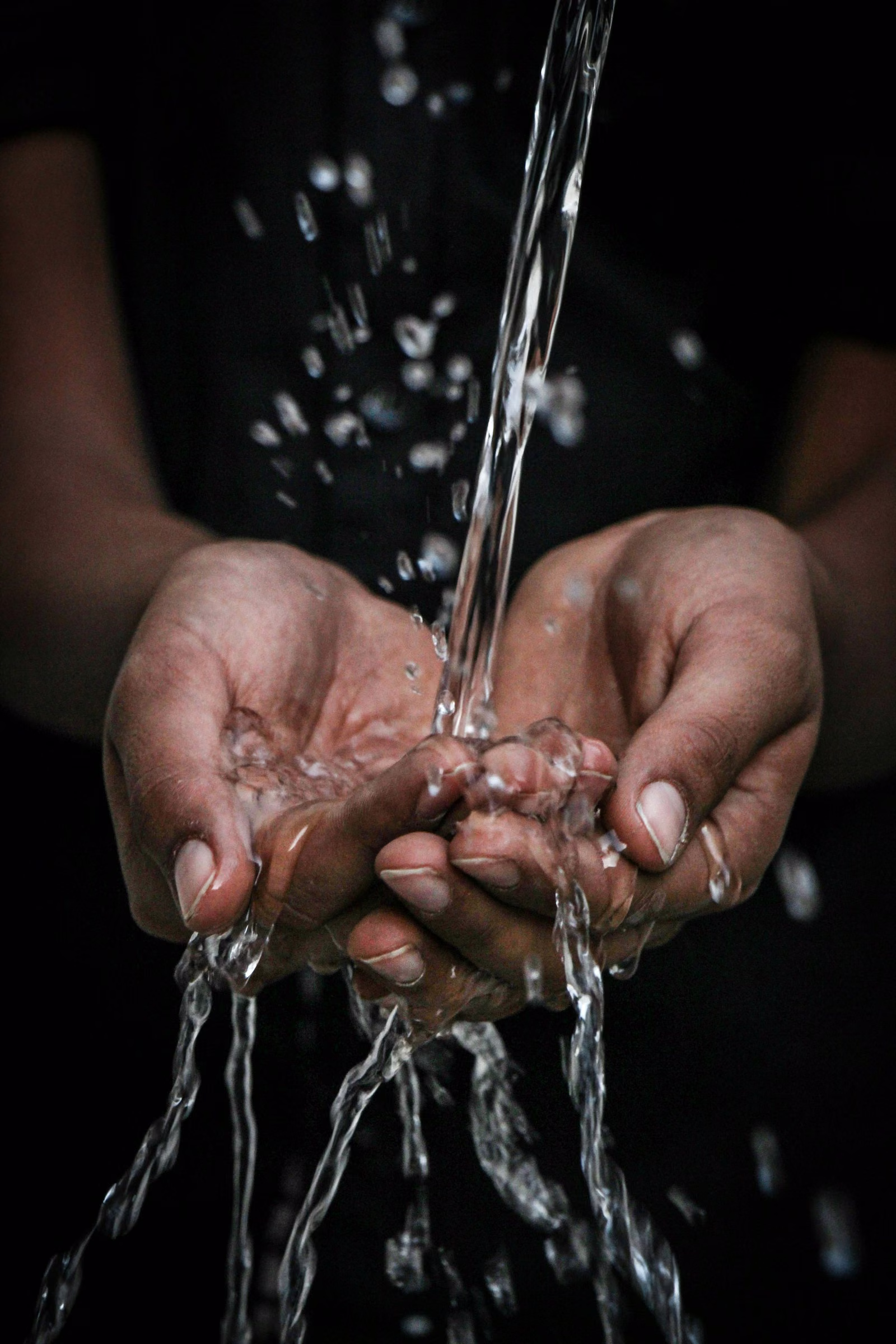 Water pouring over cupped hands.