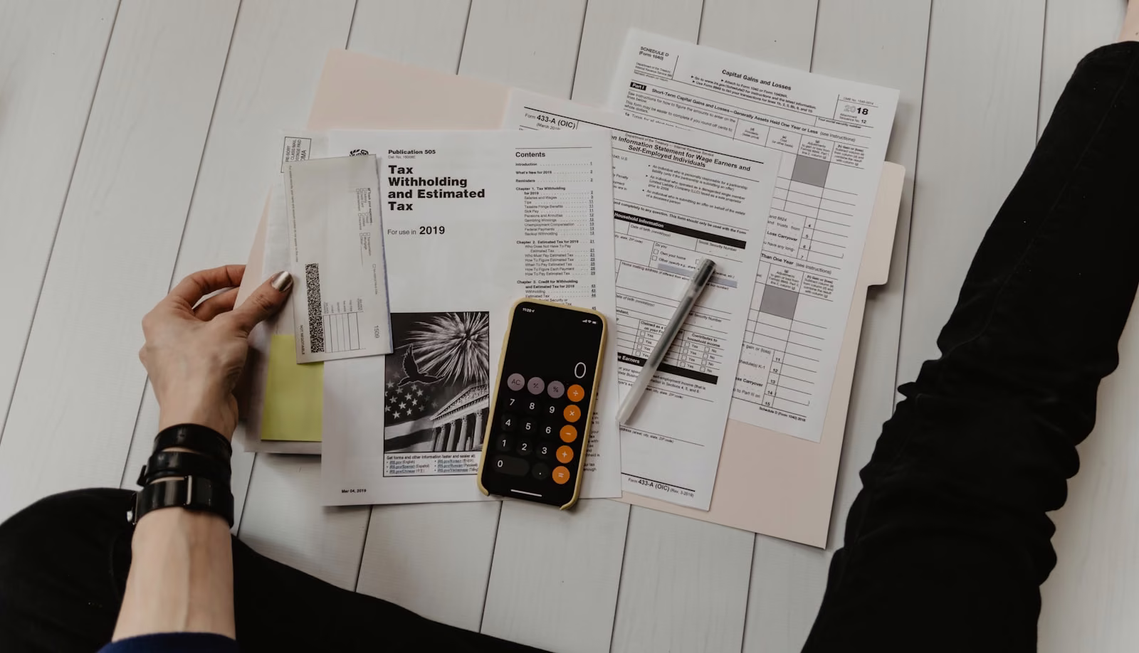 A person sorting bills and financial paperwork with a calculator.